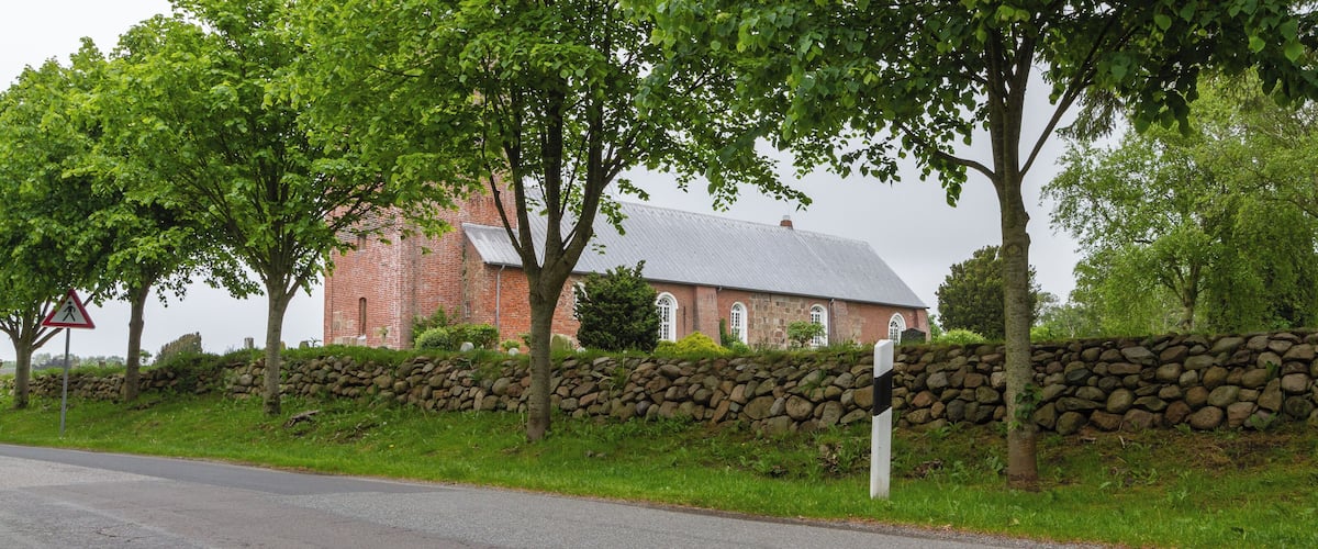 A stone wall, a red brick building, and trees.