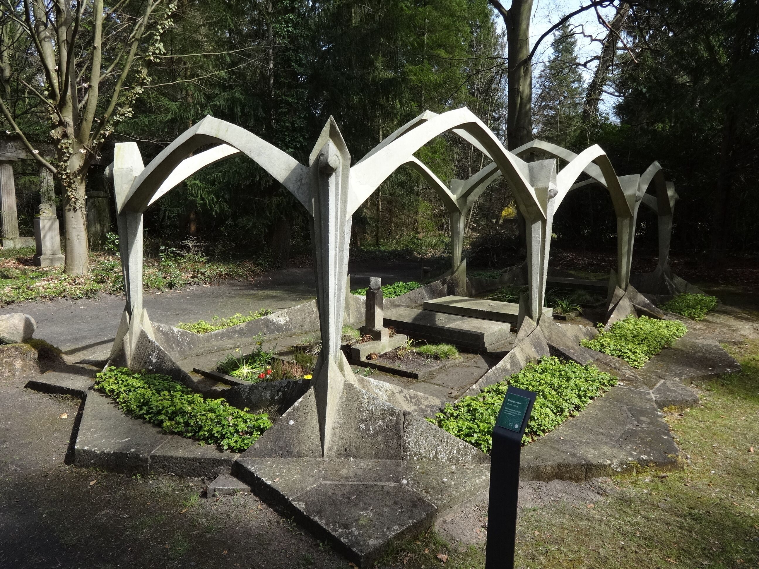 A metal sculpture with arches in a park.