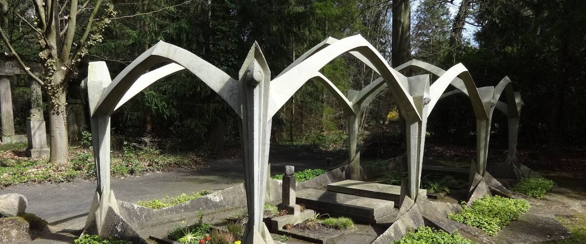 A metal sculpture with arches in a park.