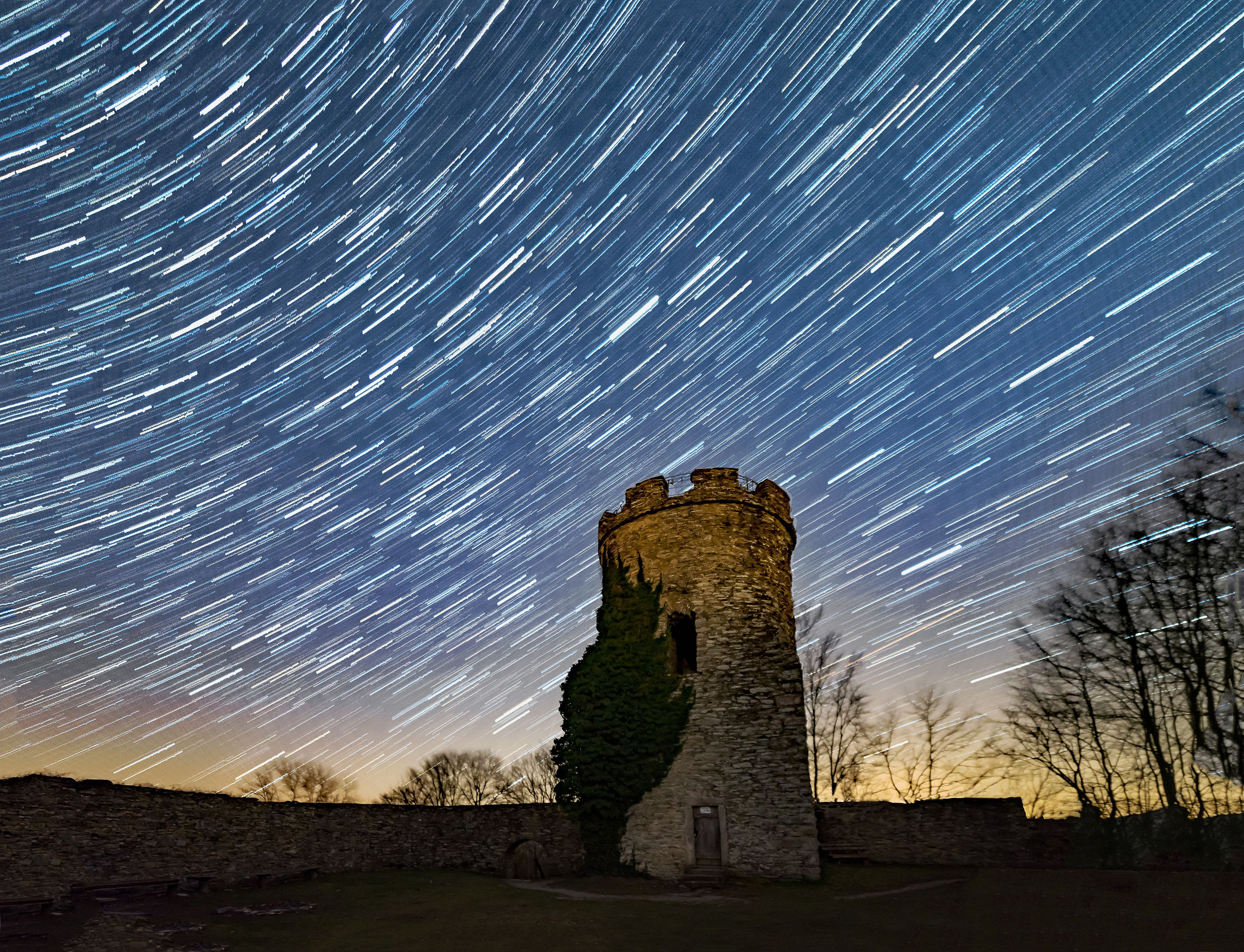 A stone tower with star trails in the night sky.