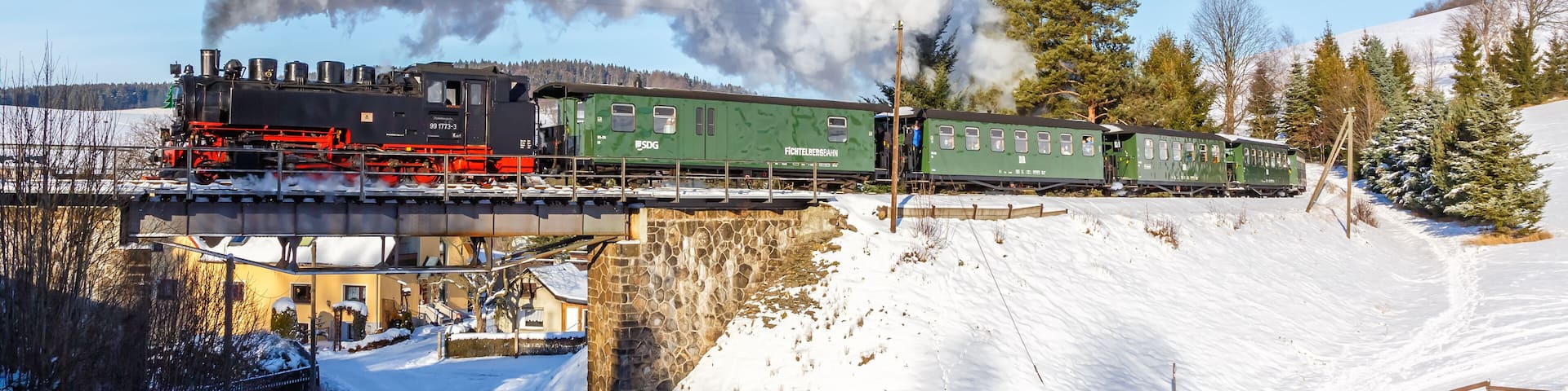 Fichtelbergbahn steam train locomotive railway on a bridge in winter in Sehmatal, Germany
