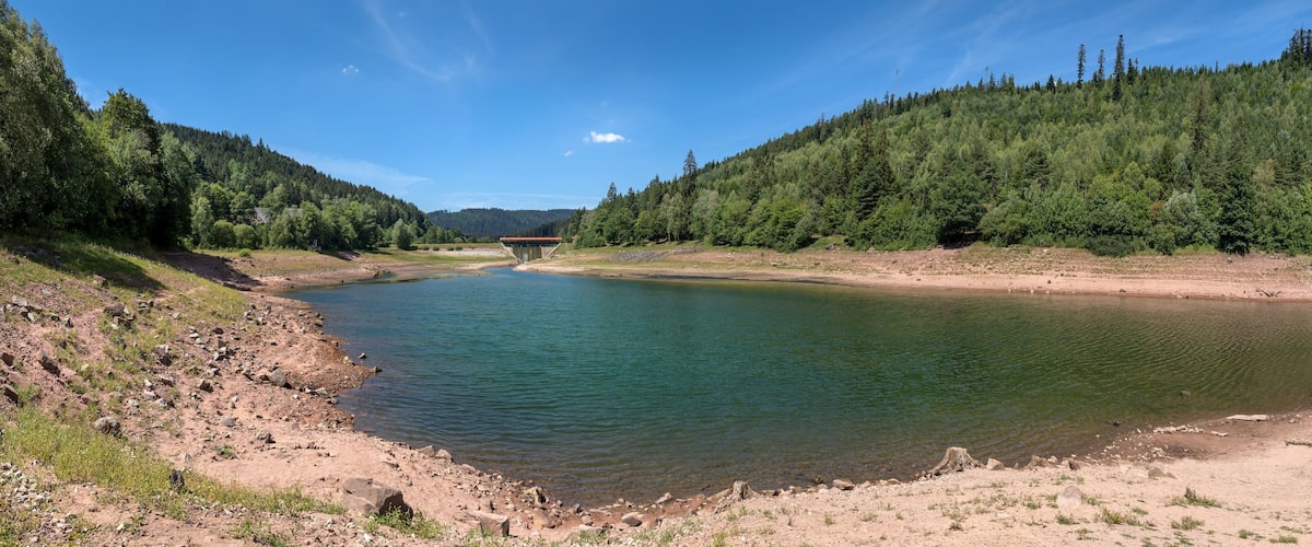 A river with a dam and forested hills.