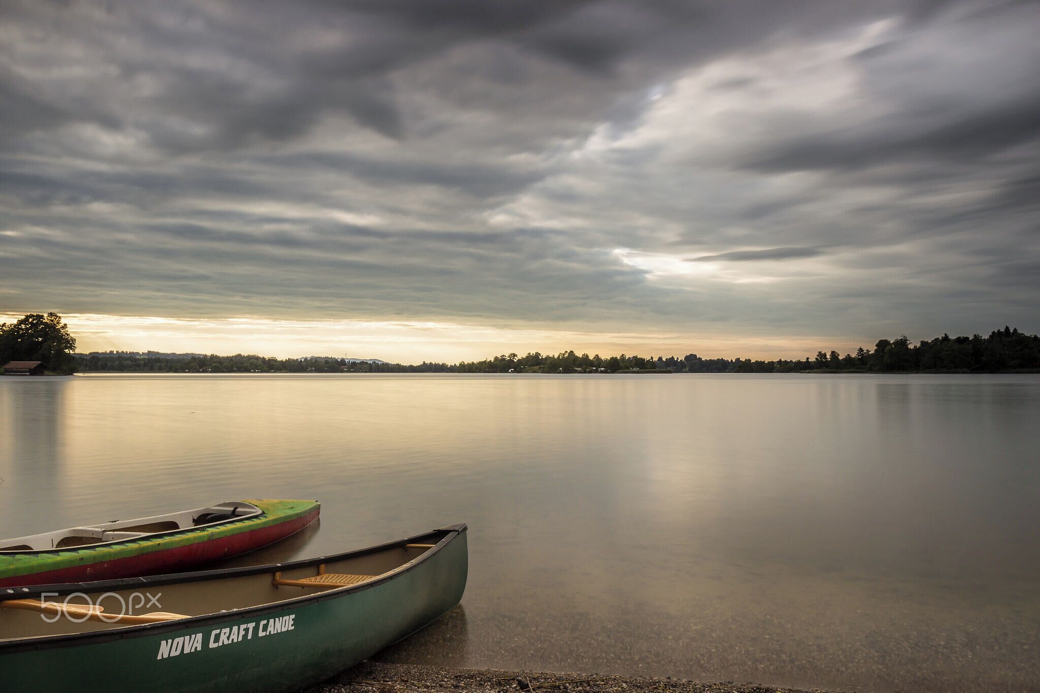 500px provided description: Kanu Im Abendlicht [#sky ,#landscape ,#sunset ,#water ,#boat ,#clouds ,#canoe ,#Sonnenuntergang ,#Abend ,#See ,#Deutschland ,#Wasser ,#Landschaft ,#Himmel ,#Wolken ,#Bayern ,#Langzeitbelichtung ,#Boot ,#Abendlicht ,#Kanu ,#Wassersport ,#Staffelsee]