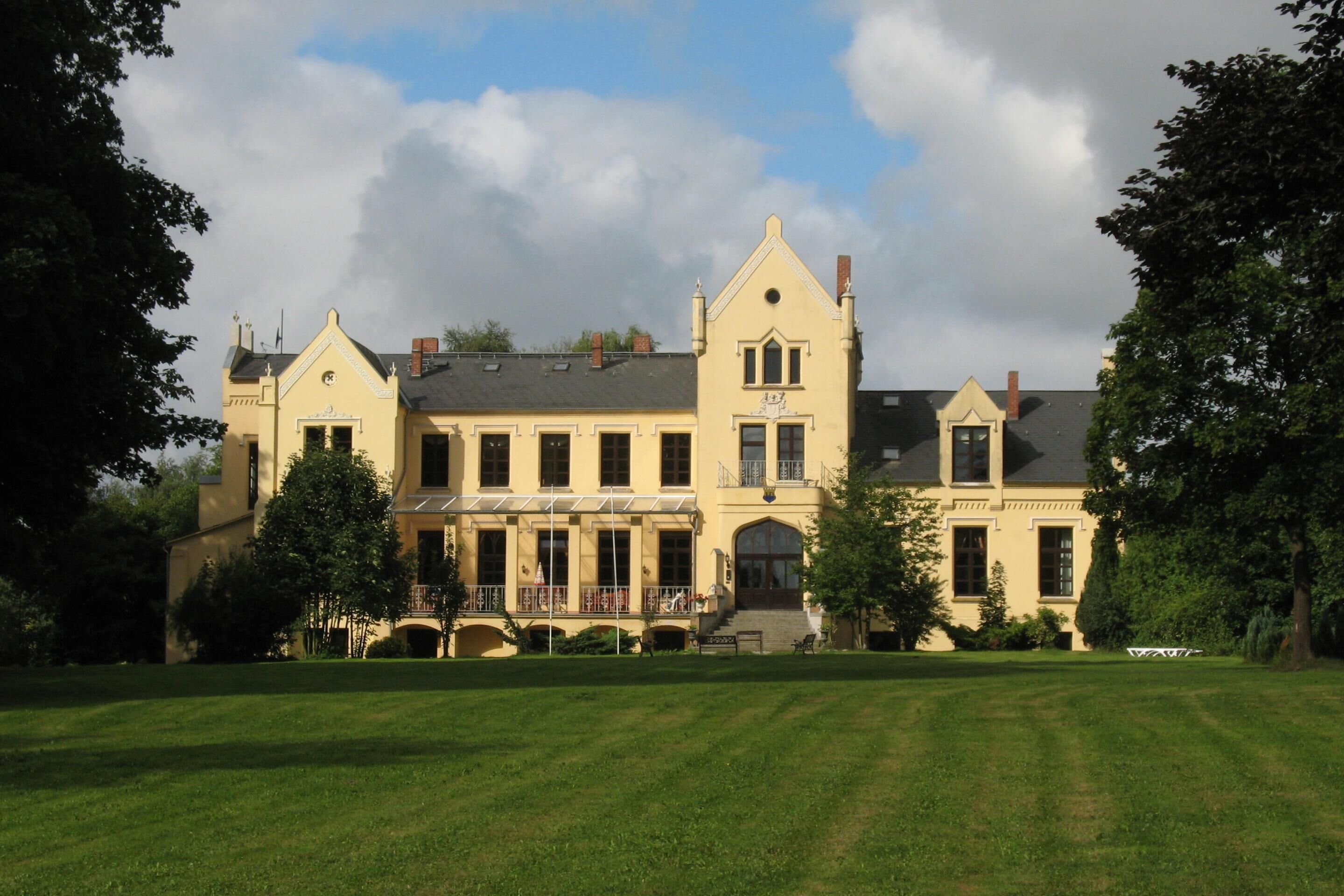 A large, yellow building with a symmetrical facade, multiple windows, and a central entrance.