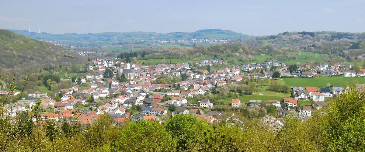 A town nestled in a valley with rolling hills in the background.