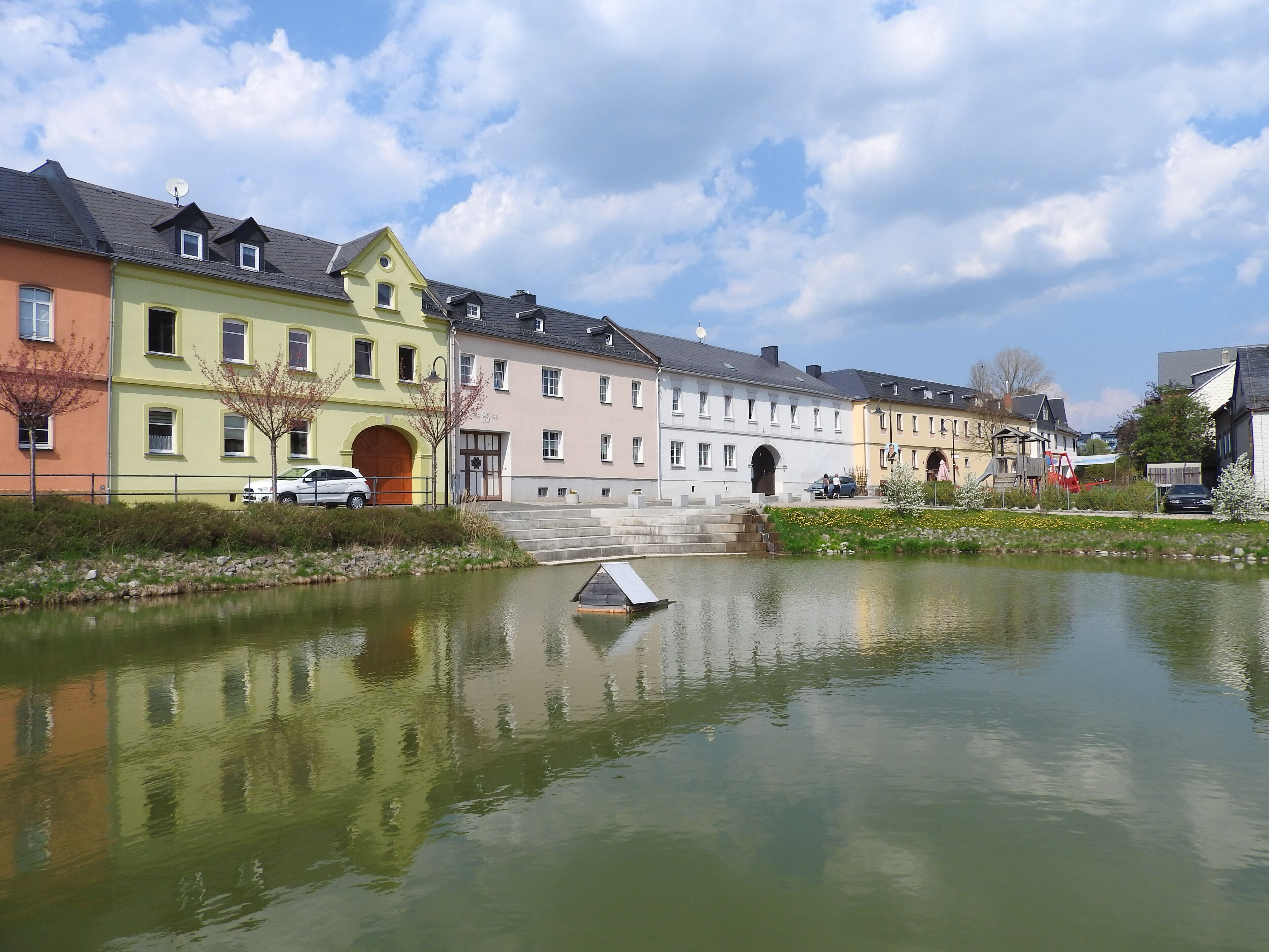 A canal with buildings reflecting on the water, a bridge, and a small boat.