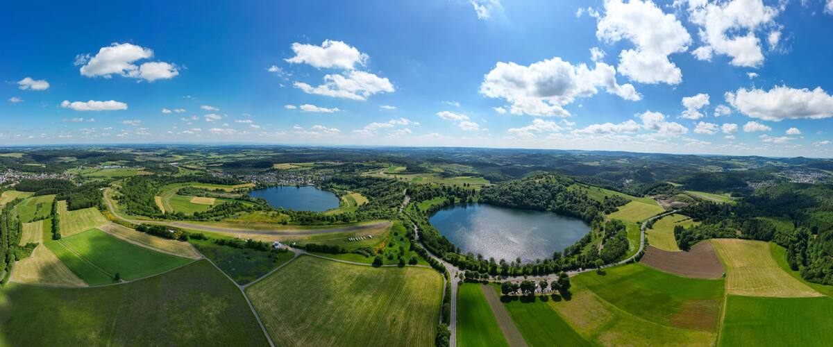 A panoramic view of a lake surrounded by green fields and a small town.