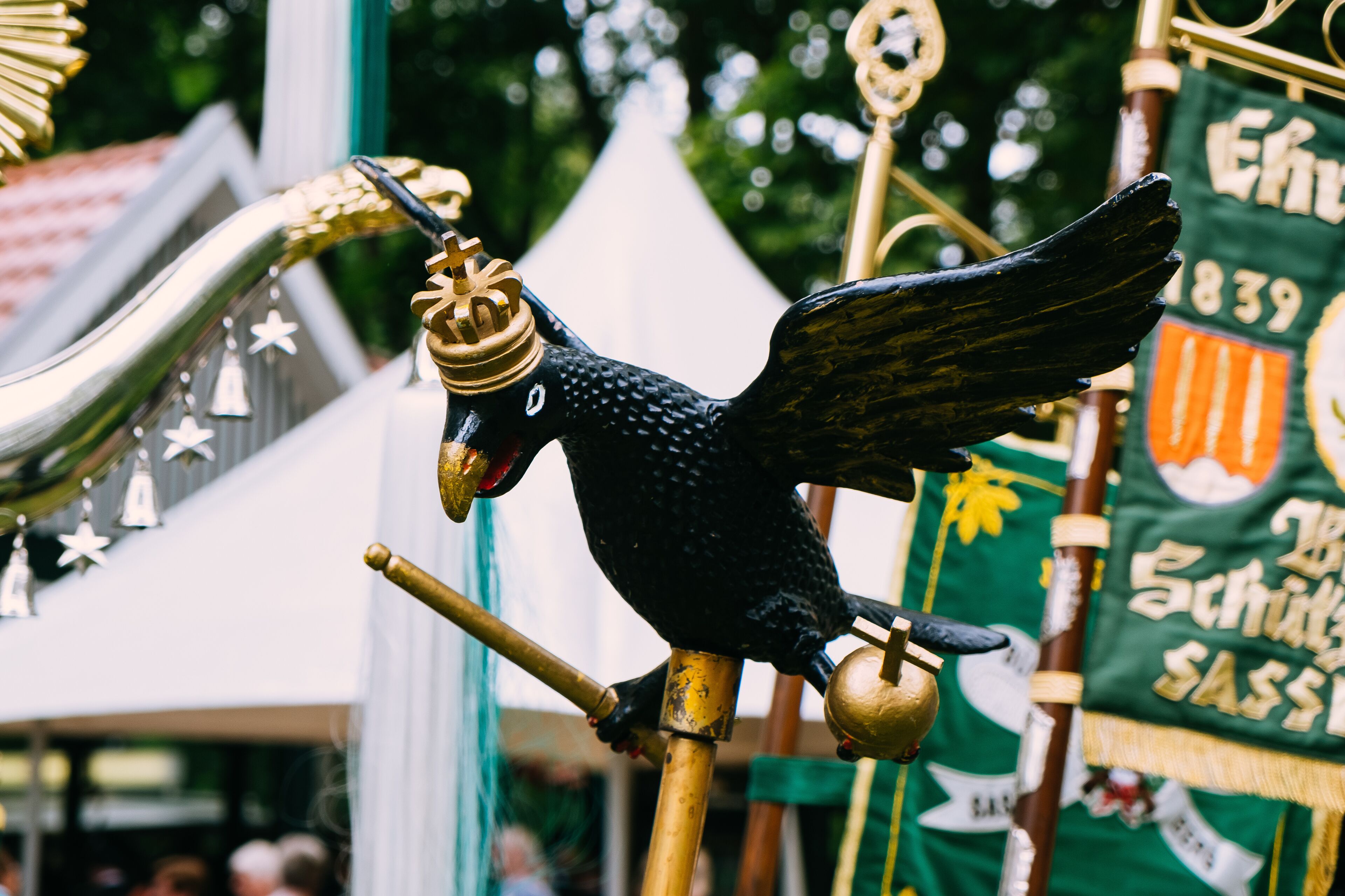 A black bird statue with wings and a crown, perched on a golden pole.
