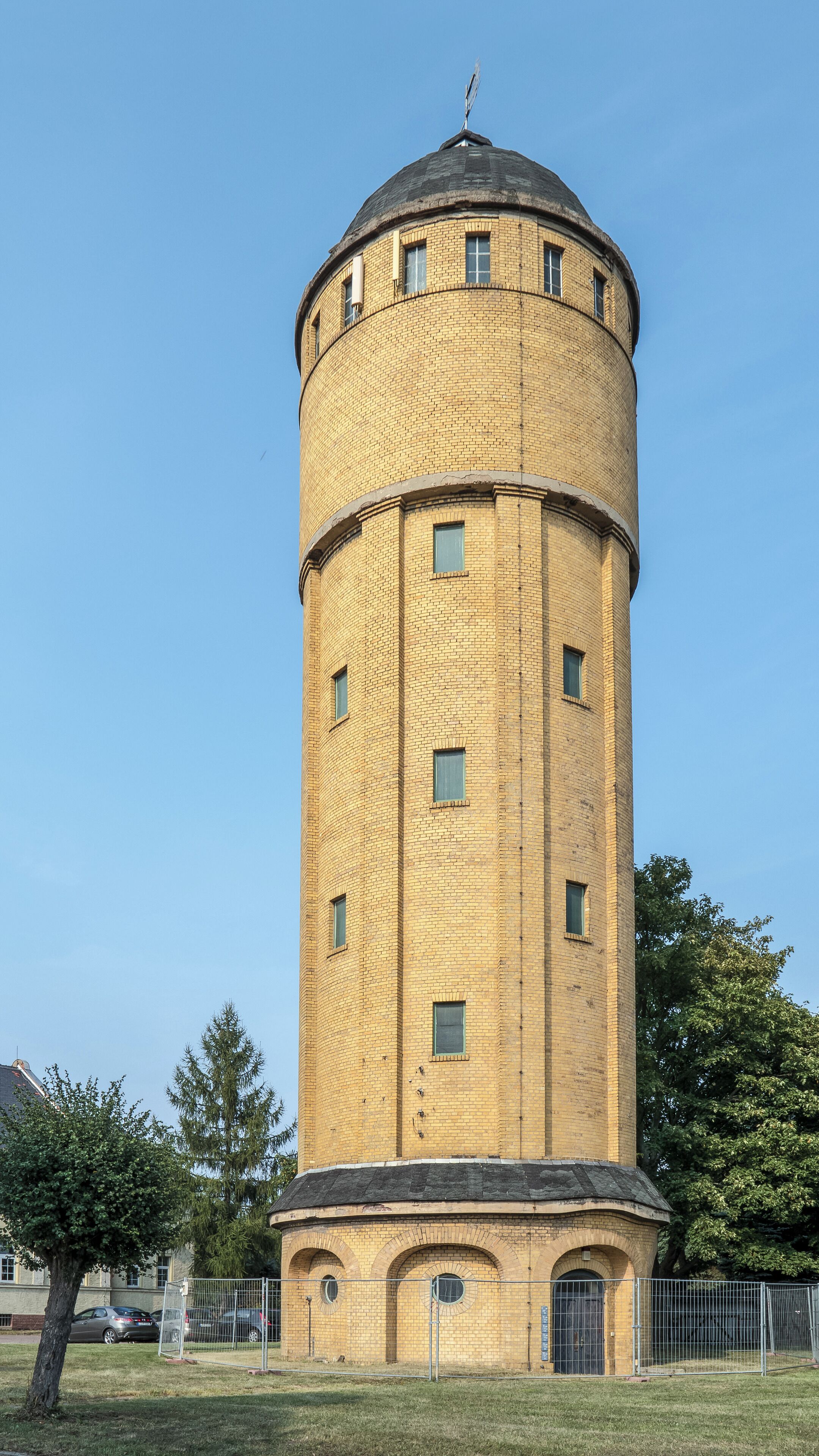 A cylindrical brick water tower with arched windows and a dome on top.