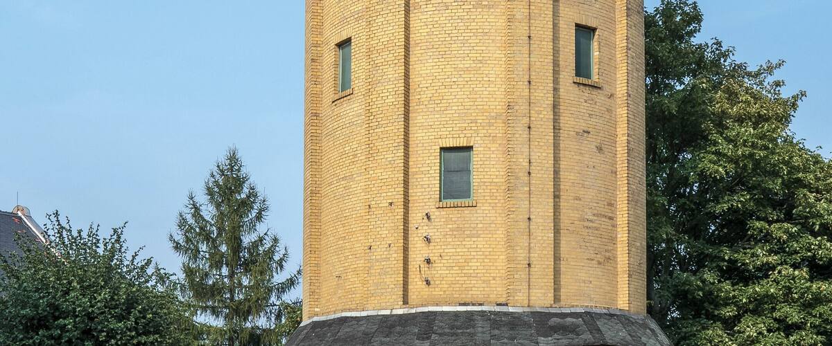 A cylindrical brick water tower with arched windows and a dome on top.