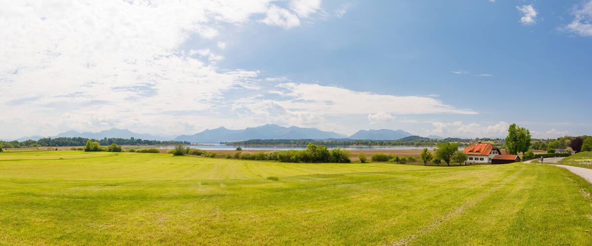A green field, a lake, and mountains in the distance.