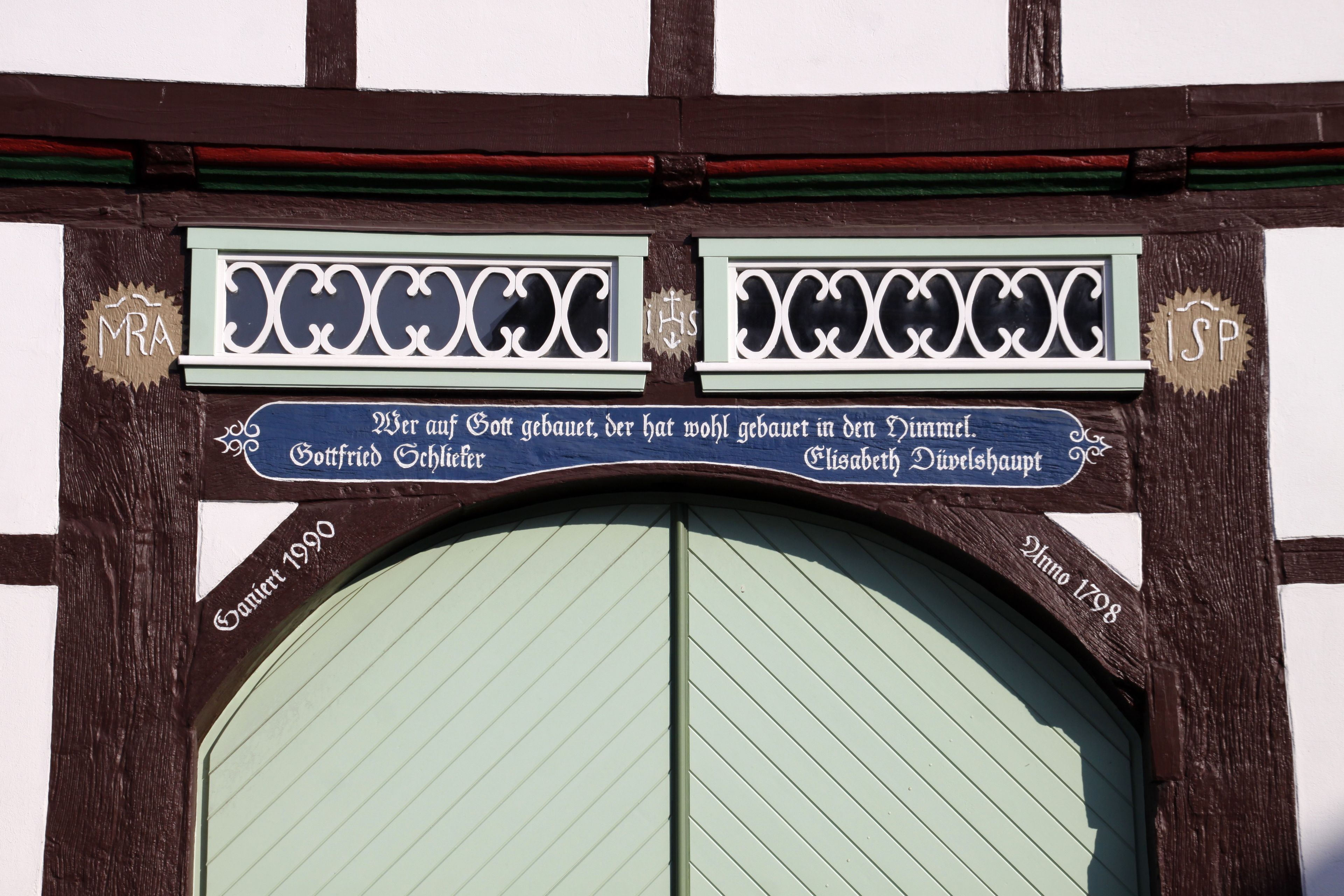 Eine traditionelle Holztür mit einem Schild darüber. Das Schild trägt den Text 'MRA' und 'ISSP' auf beiden Seiten.