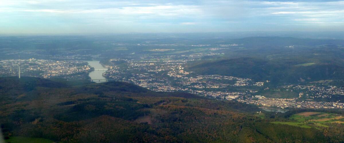 An aerial view of a river winding through a town surrounded by hills.
