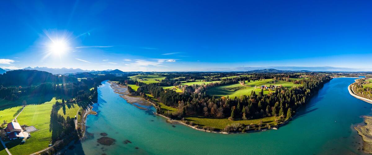 A river winding through a valley with green fields and a forested area.