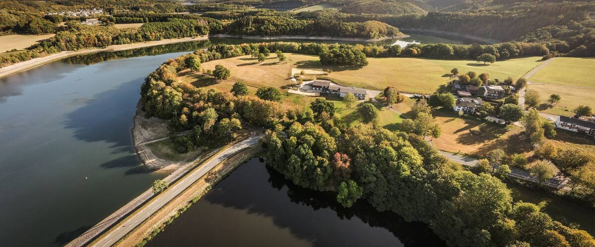 A river curving through a landscape with a bridge, surrounded by trees and fields.