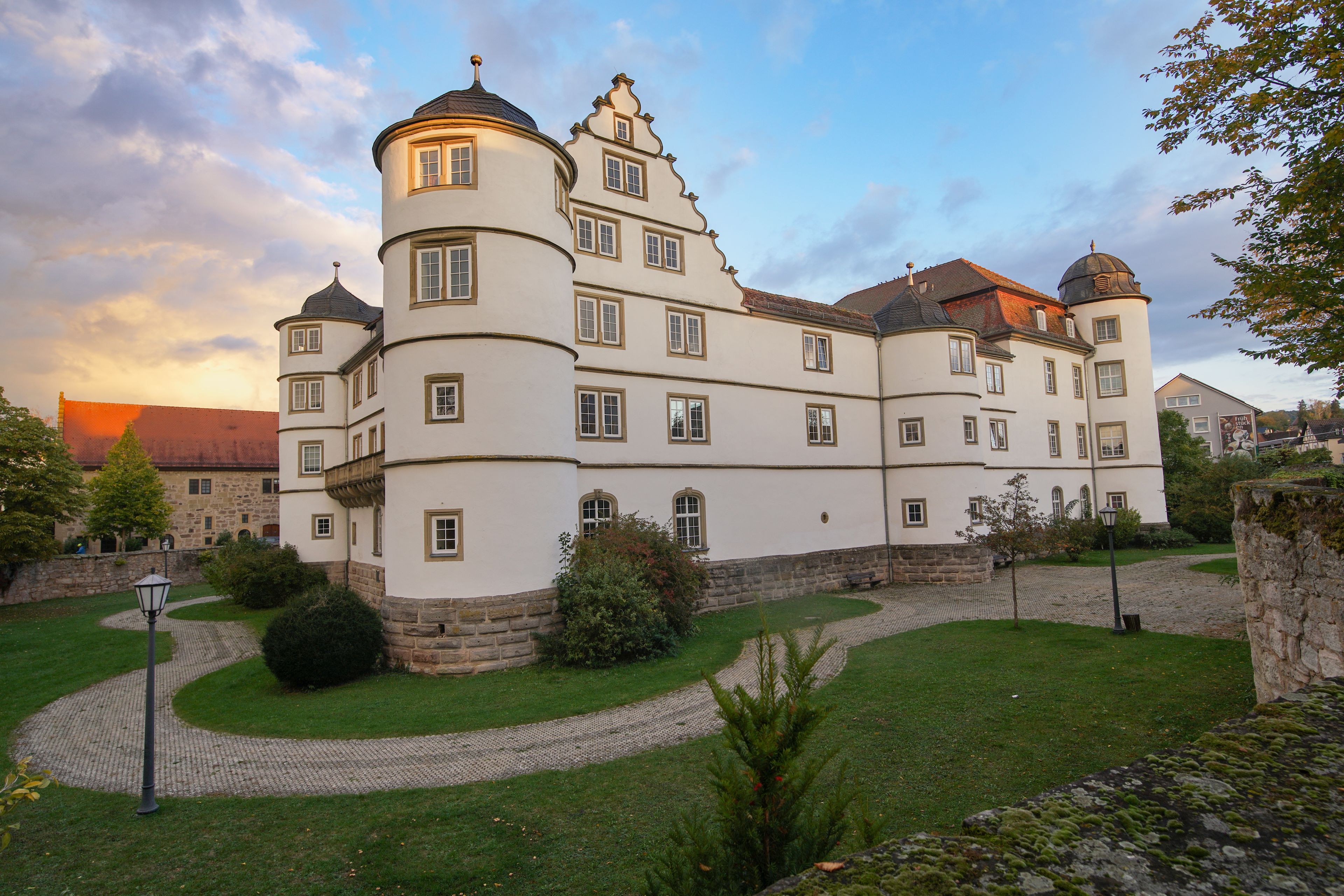 A large, historic building with multiple towers and a well-maintained garden.