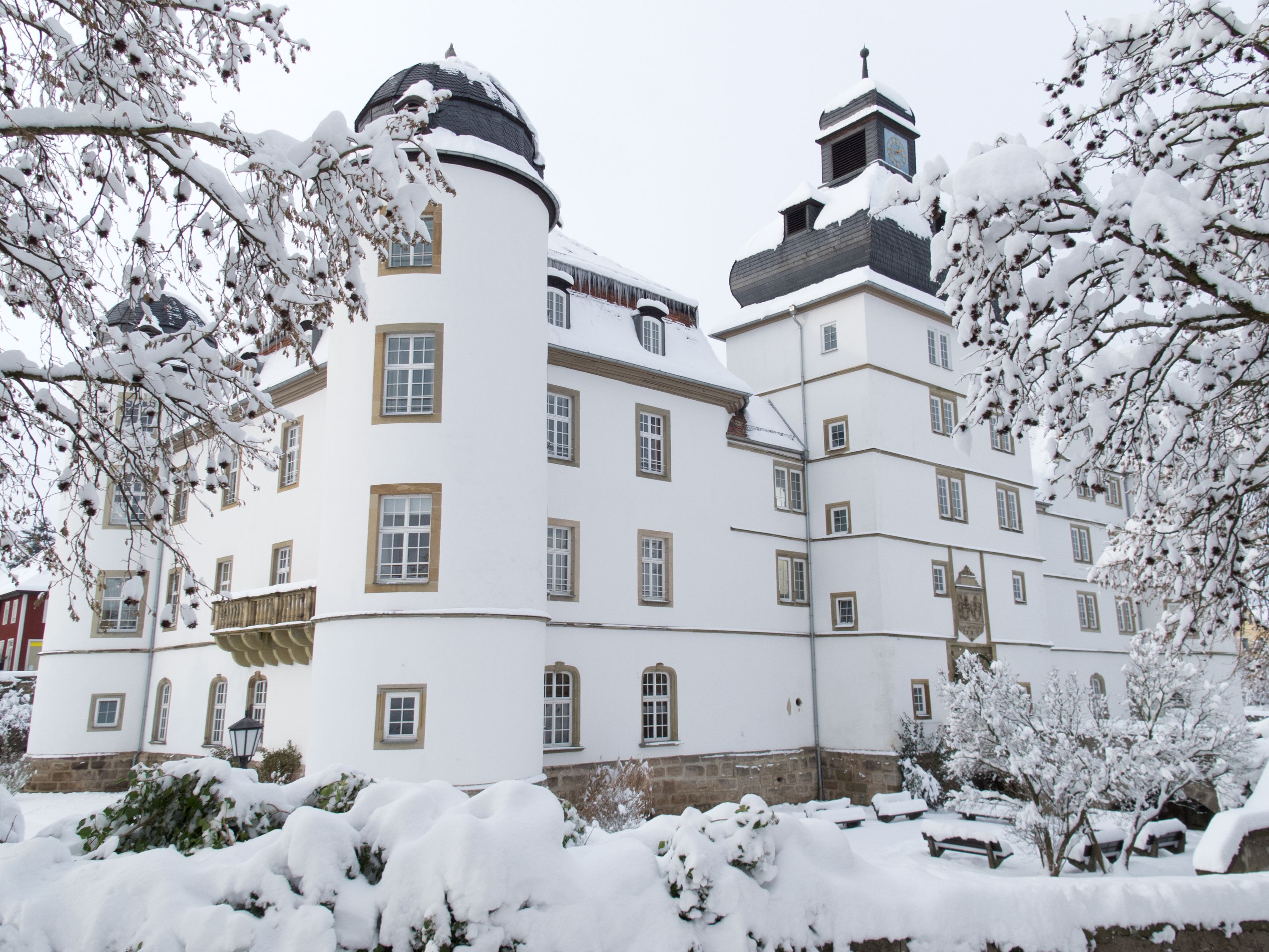 A snow-covered building with multiple windows and a clock tower.