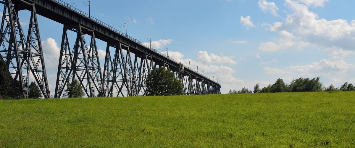 A steel bridge over a grassy field with a clear sky.