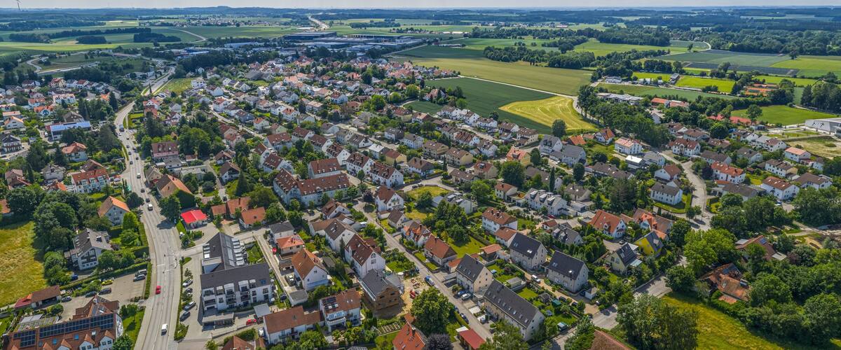 An aerial view of a residential area with houses, roads, and green fields.