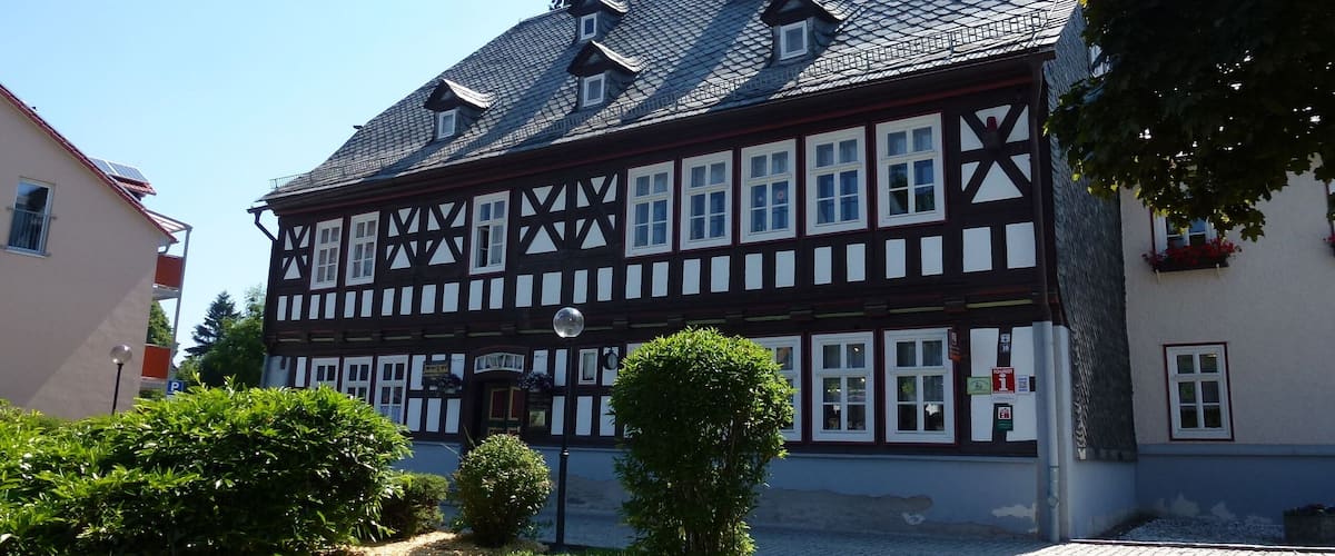 A traditional half-timbered building with a tiled roof and a small garden in front.