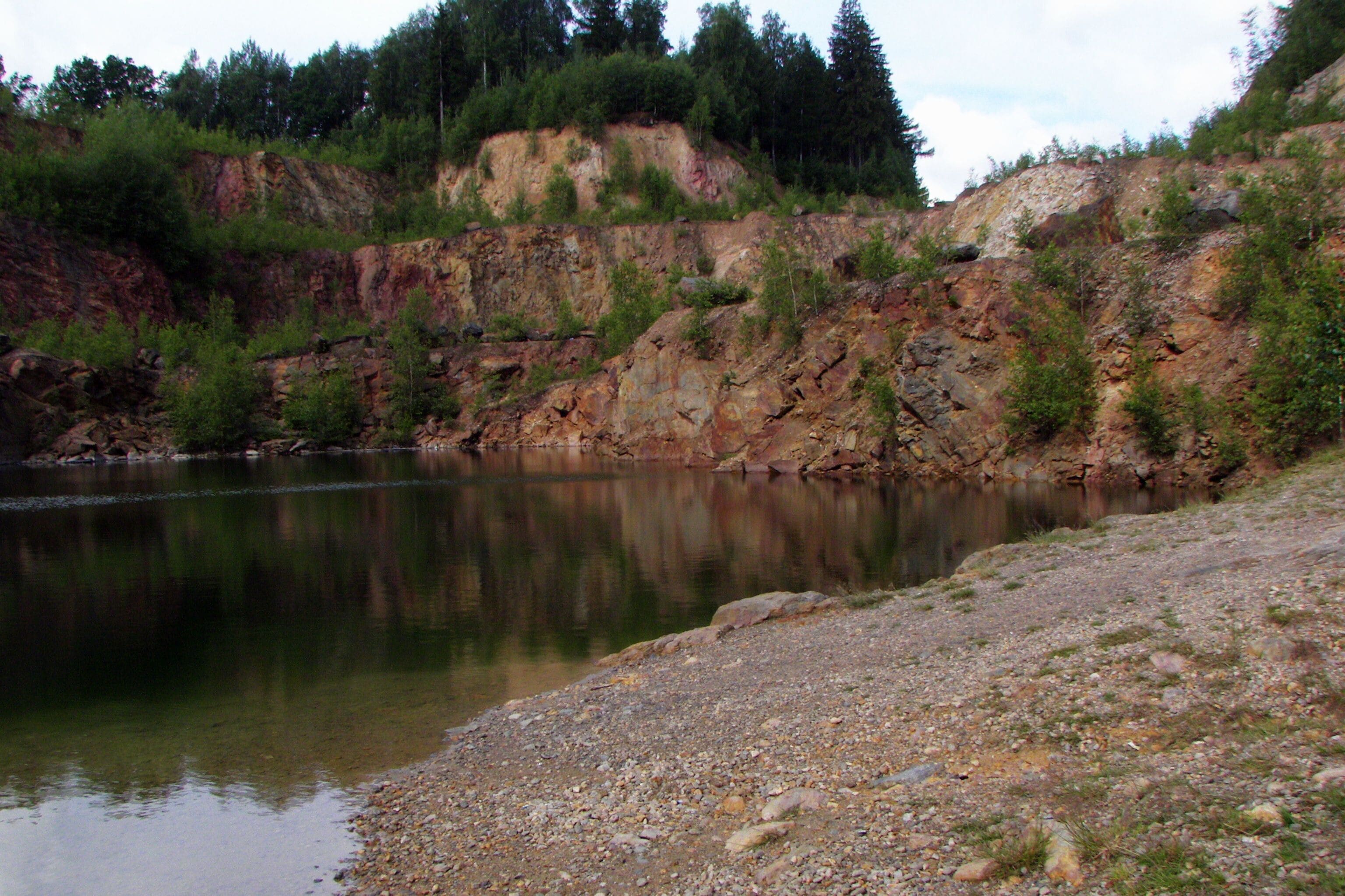 A calm river with rocky cliffs and sparse vegetation.