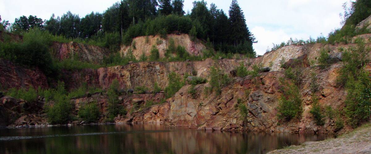 A calm river with rocky cliffs and sparse vegetation.