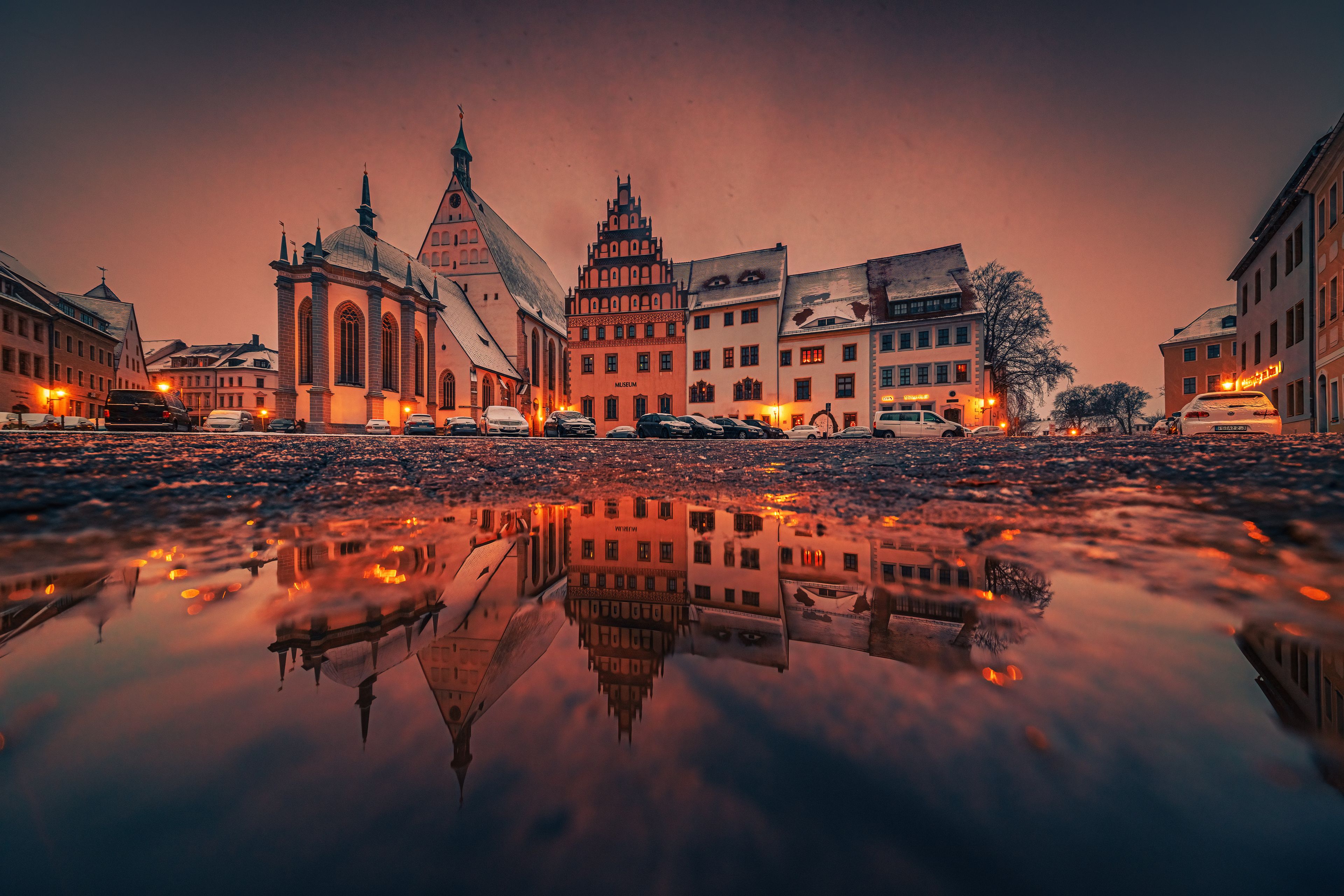 A cityscape with a church, a museum, and a reflection in a puddle.