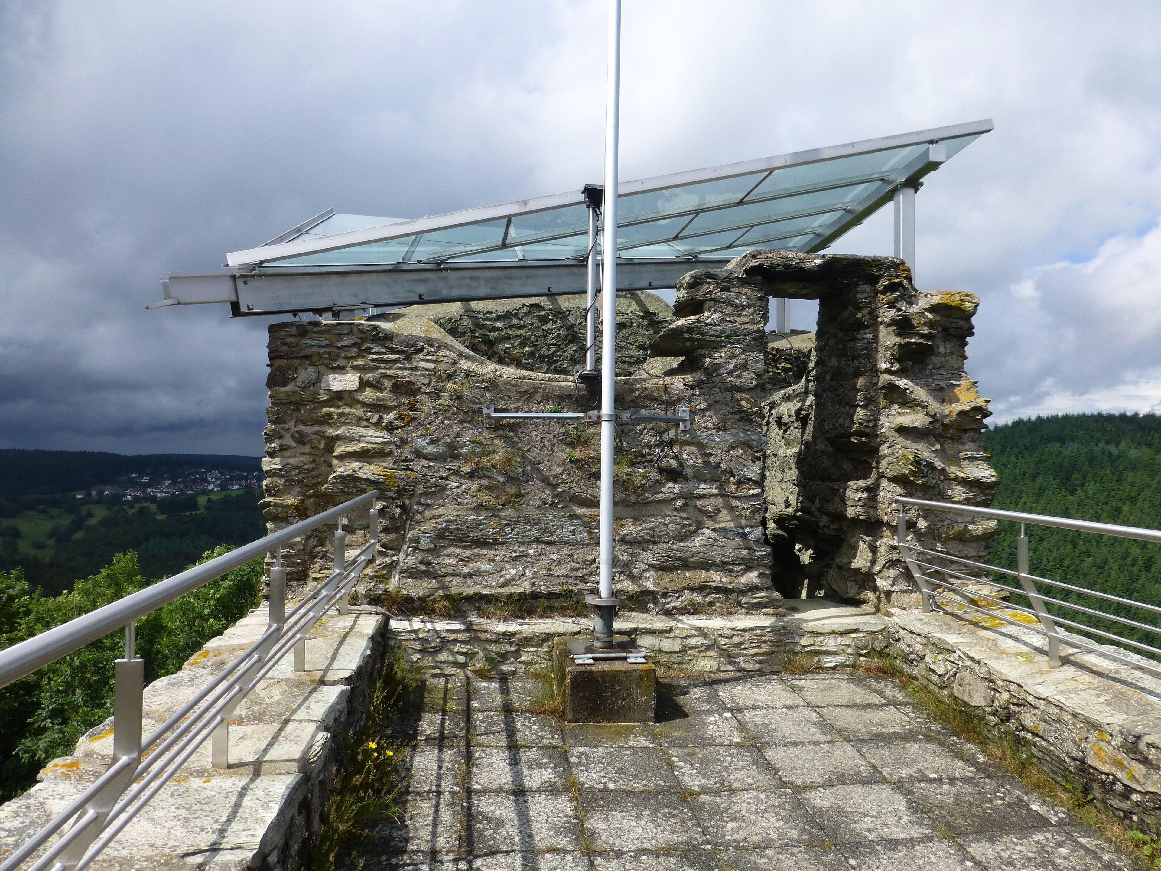 A stone structure with a metal railing and a glass roof.