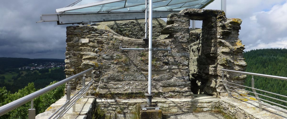 A stone structure with a metal railing and a glass roof.
