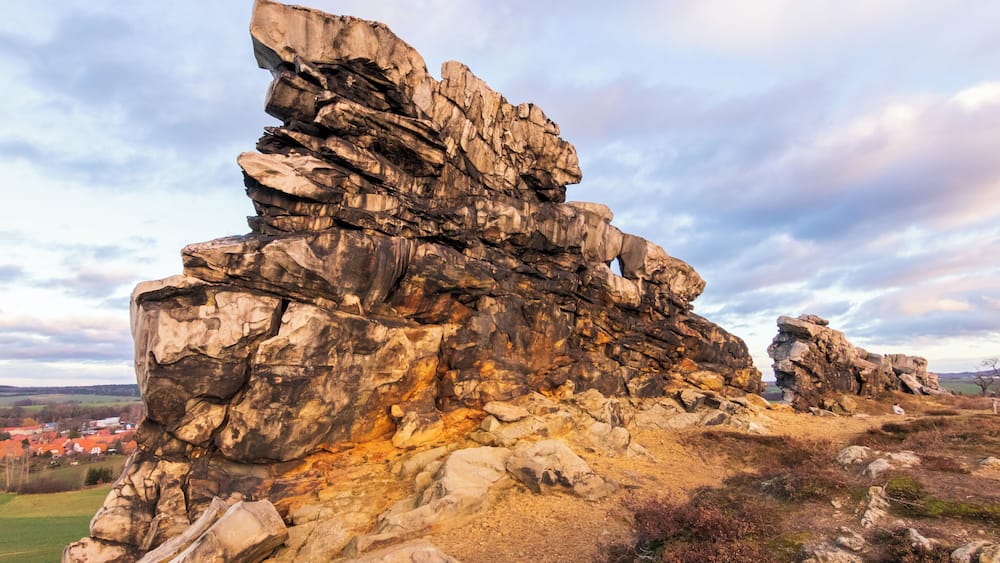 A rocky outcrop with layered rock formations and a distant village.