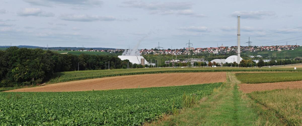 A rural landscape with fields, a white building, and a distant town.