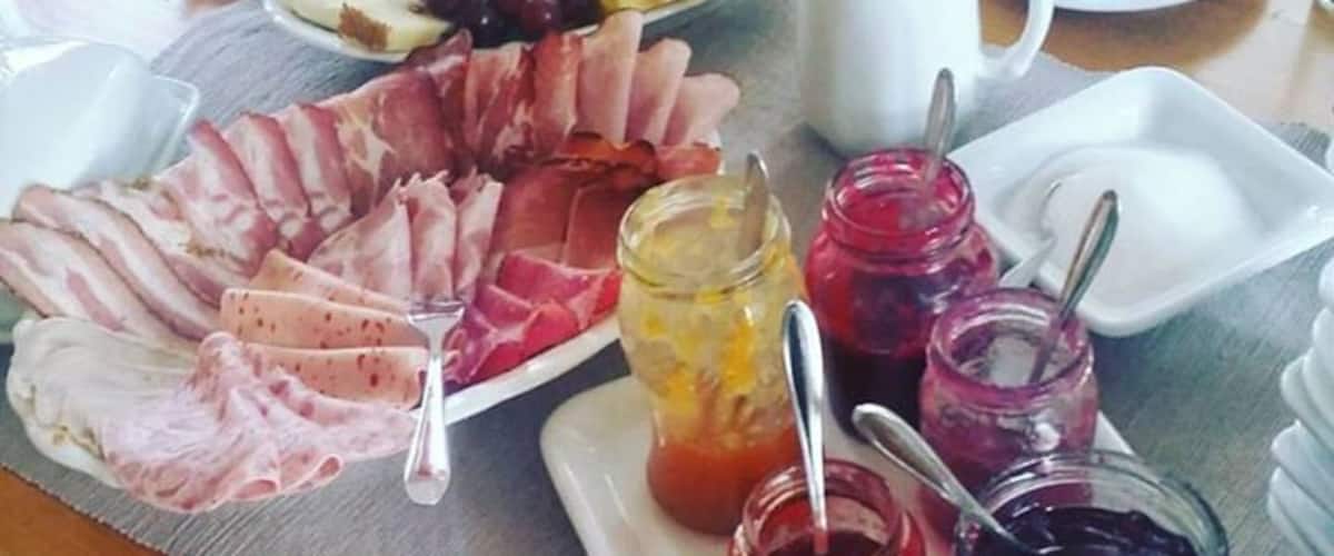 A table with a charcuterie board, cheese, grapes, and various jams.