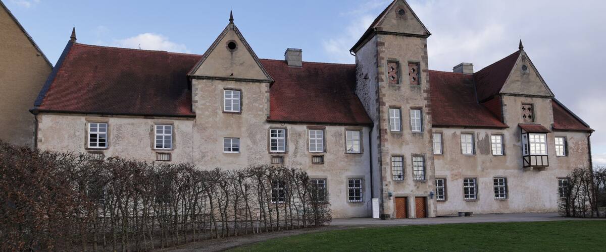 A large, historic building with a red-tiled roof and multiple windows.