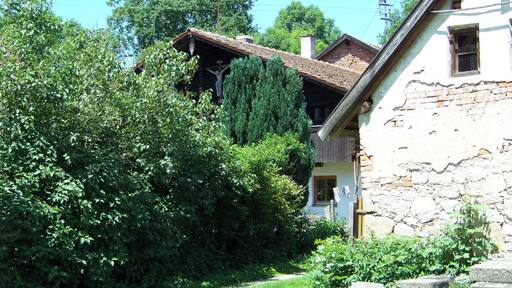 Metten, Zeitldorf 6. Wohnstallhaus. Erdgeschossiger Flachsatteldachbau mit hohem Blockbau-Kniestock, Giebelschrot, geschnitzten Schrotsäulen und Giebelkruzifix, Ende 18. Jahrhundert.