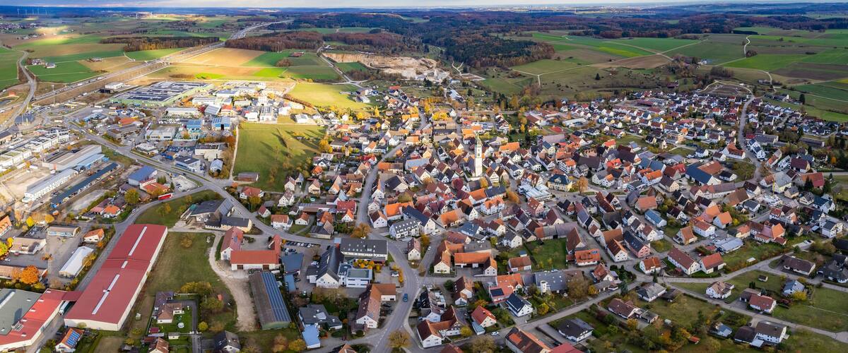 An aerial view of a town with a mix of residential houses, industrial buildings, and green fields.