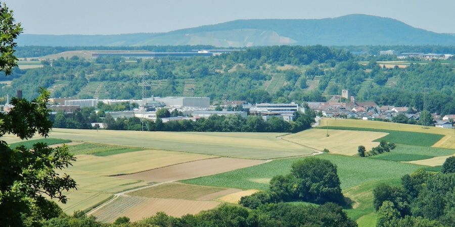 Ländliche Landschaft mit Feldern, einer kleinen Stadt und fernen Bergen.