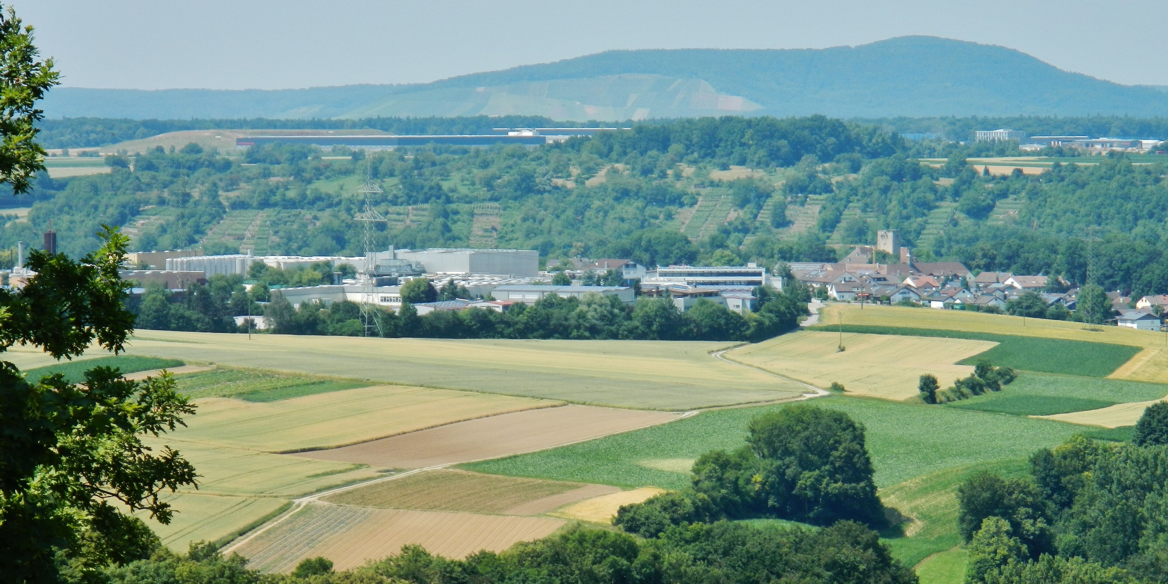 A rural landscape with fields, a small town, and distant mountains.
