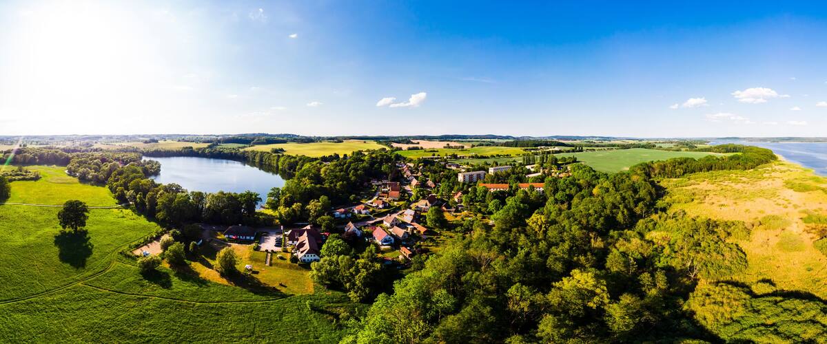 A lakeside village with houses and greenery.