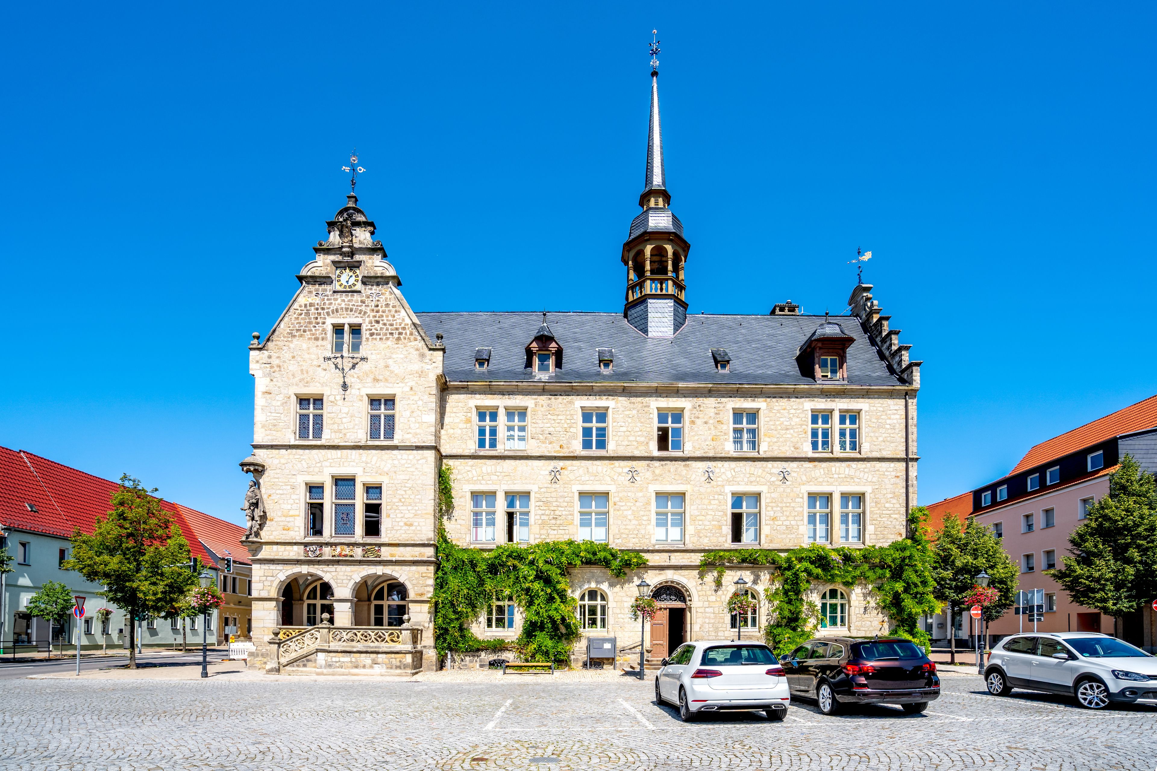 A historic stone building with a clock tower and a red-tiled roof.