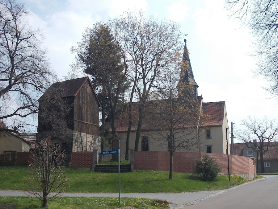 Una iglesia con campanario y un granero de madera.
