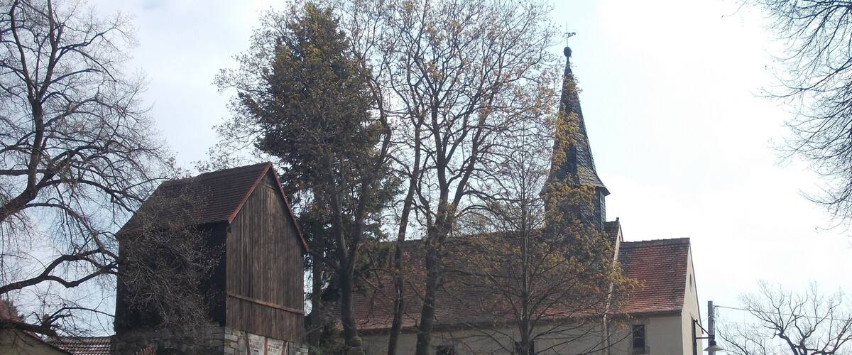 A church with a steeple and a wooden barn.