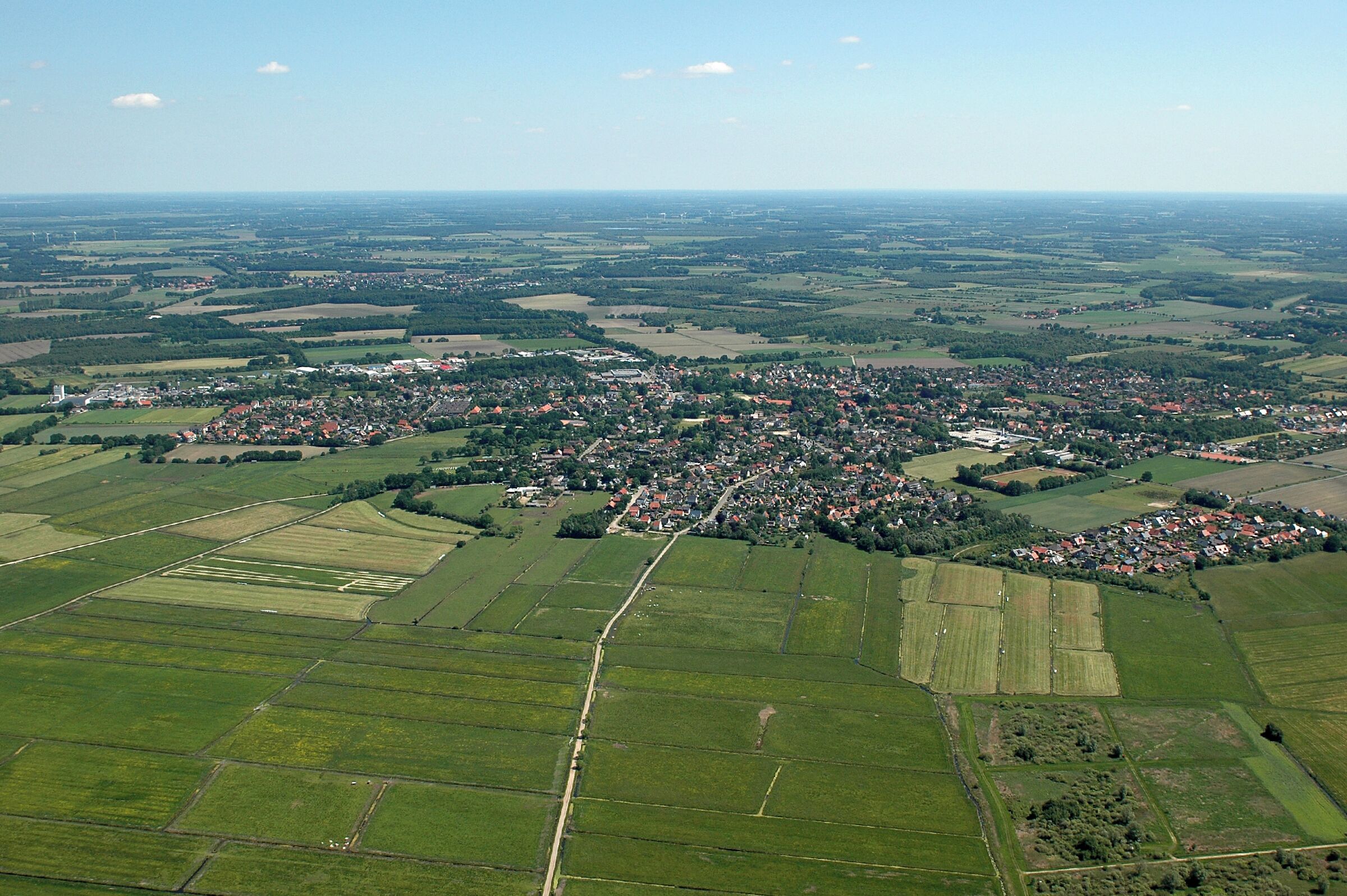 An aerial view of a rural town surrounded by fields and farmland.