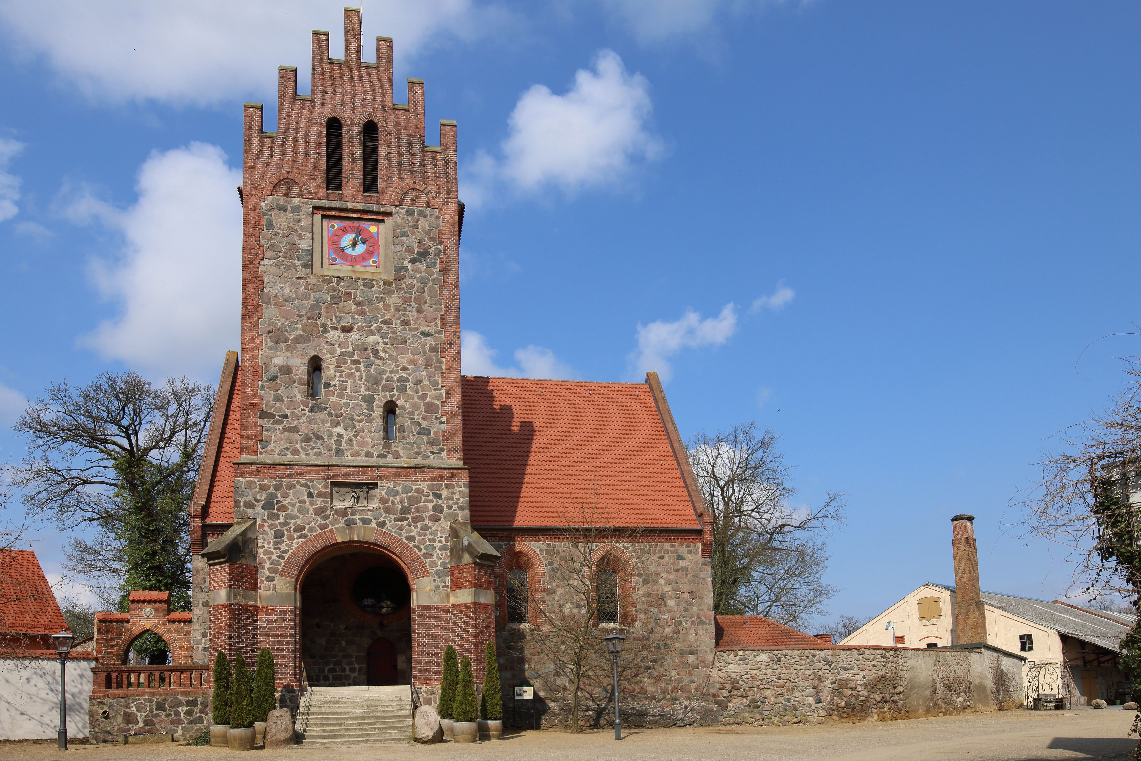Una iglesia histórica con una torre alta, un reloj y un tejado de tejas rojas.