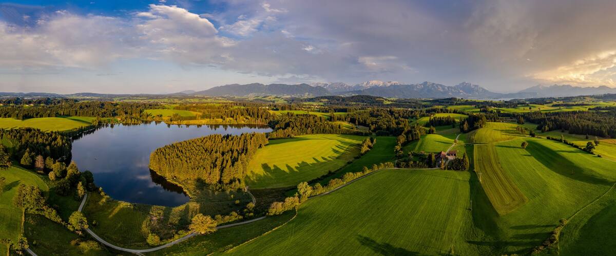 A golf course with a lake, rolling hills, and mountains in the background.