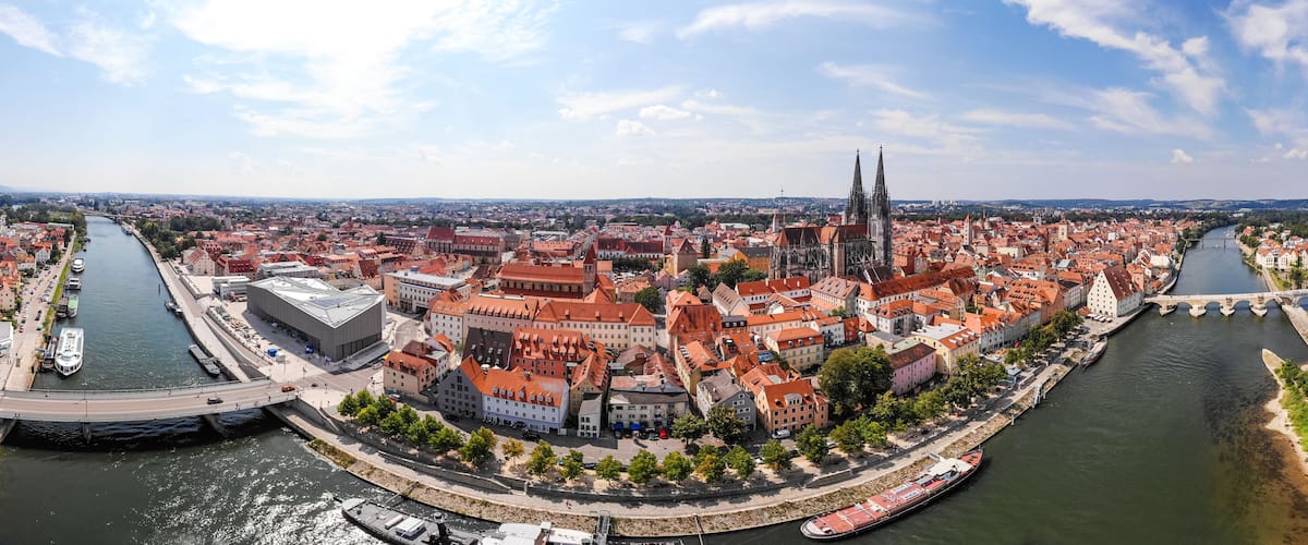 A panoramic view of a city with a river, historic buildings, and a prominent cathedral with twin spires.