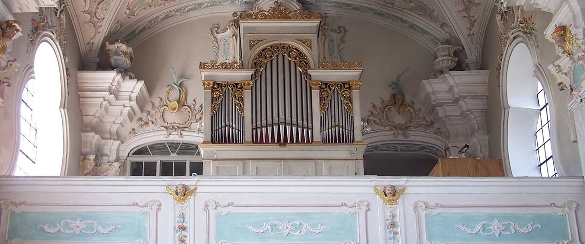 An ornate organ with intricate carvings and a decorative ceiling with frescoes.