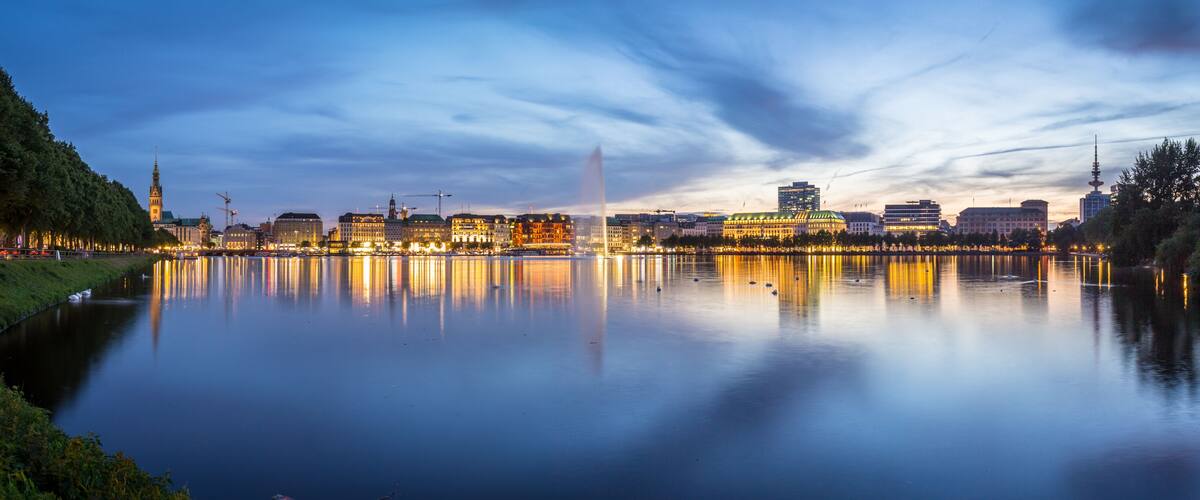 A calm river reflecting city lights, a prominent tower, and a bridge.