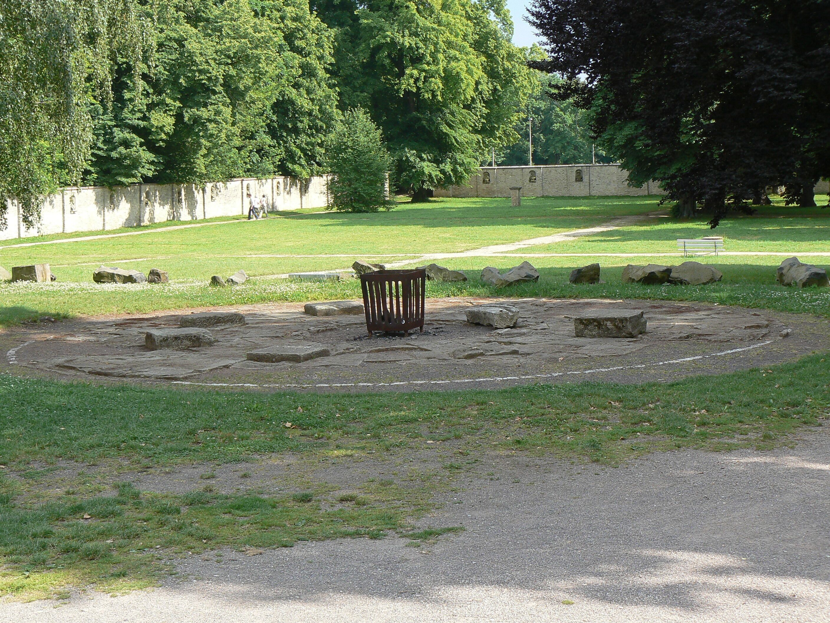 A circular stone structure surrounded by grass and trees in a park.