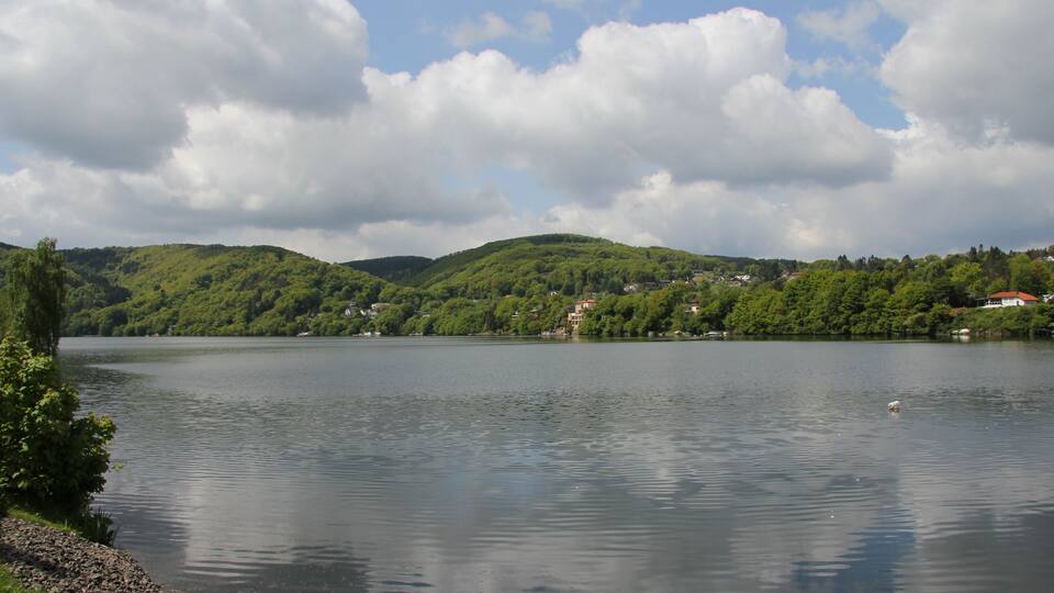A calm lake surrounded by green hills and houses.