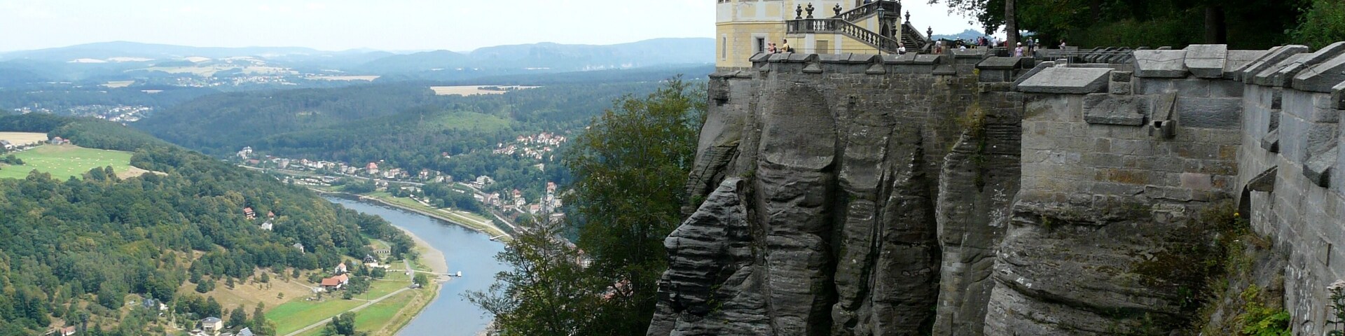 Un castillo en lo alto de un acantilado rocoso con vistas a un río y un valle.